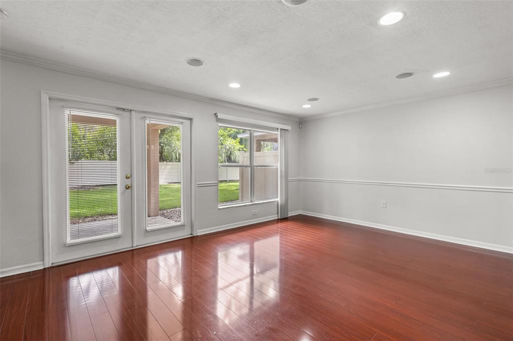 An empty room features hardwood floors, white walls with chair rail molding, and glass doors — 2972 ROYAL TUSCAN LANE, VALRICO, FL