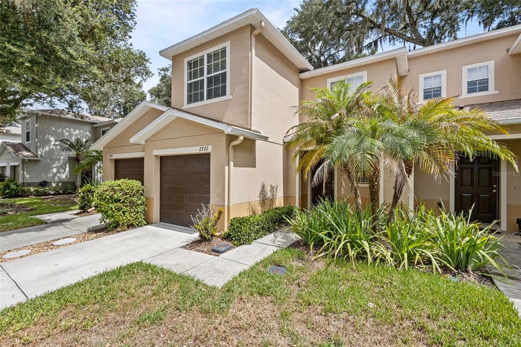 A two-story townhouse with a tan stucco exterior, a single-car garage, and a palm tree — 2972 ROYAL TUSCAN LANE, VALRICO, FL