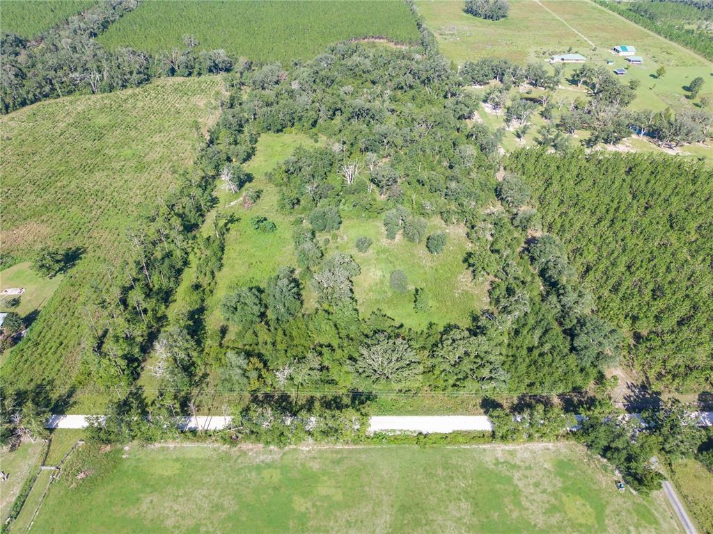 An aerial view shows a wooded lot surrounded by open fields and a paved road — 3901 181ST ROAD, LIVE OAK, FL