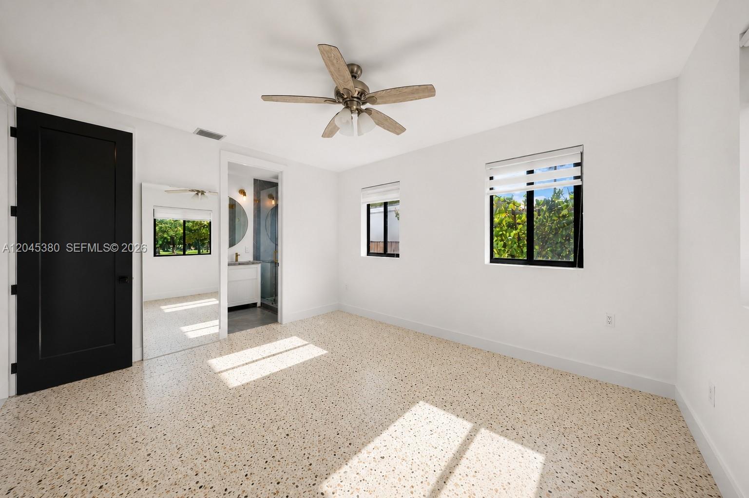 A bedroom with white walls, terrazzo flooring, a ceiling fan, and an attached bathroom — 365 Fairway Dr, Miami Beach FL 33141, MIAMI BEACH, FL