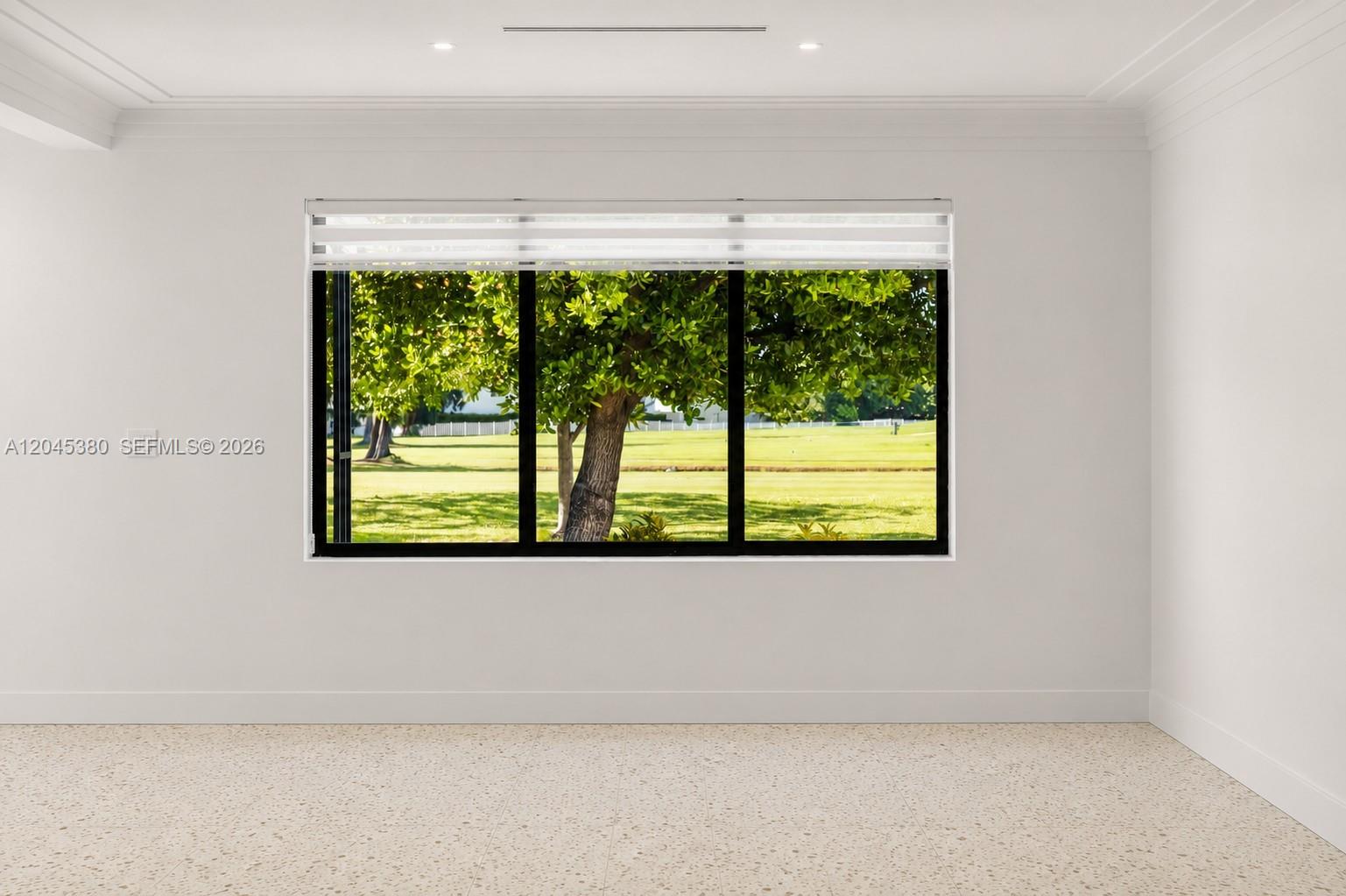 An empty room with white walls, terrazzo flooring, and a large window overlooking a golf course — 365 Fairway Dr, Miami Beach FL 33141, MIAMI BEACH, FL