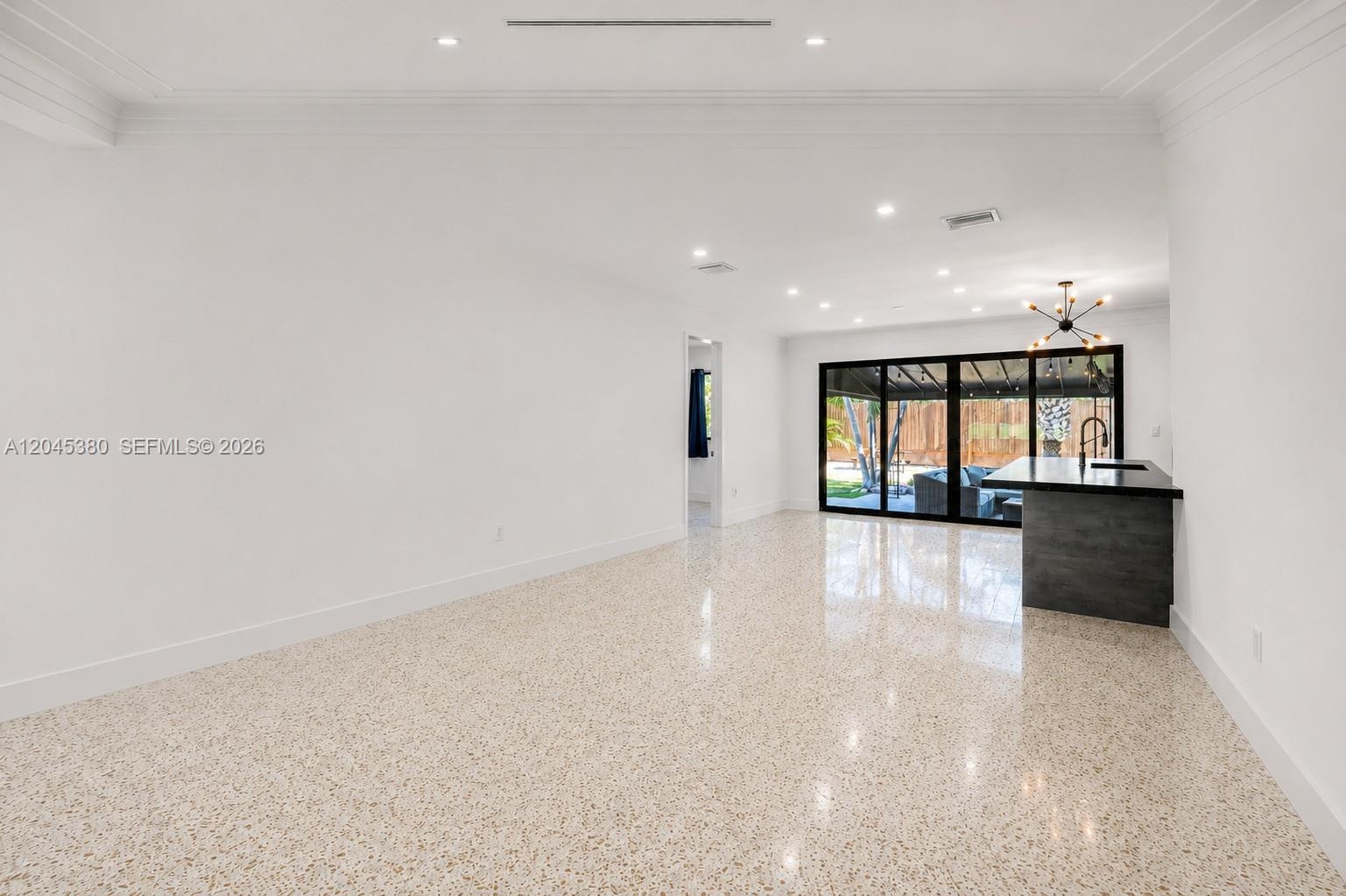 A bright, open-concept room features white walls, terrazzo flooring, and a dark kitchen island — 365 Fairway Dr, Miami Beach FL 33141, MIAMI BEACH, FL