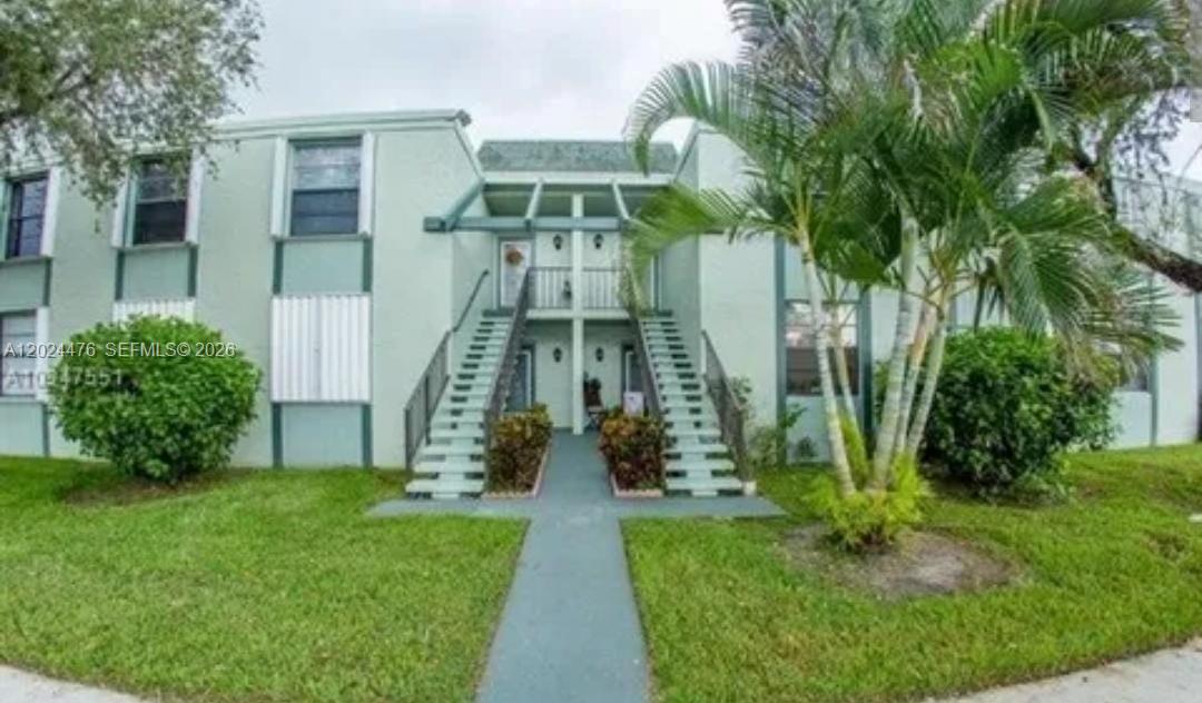 A two-story apartment building with light green stucco walls and dual exterior staircases — 7396 NW 18th St # 104, Margate FL 33063, MARGATE, FL