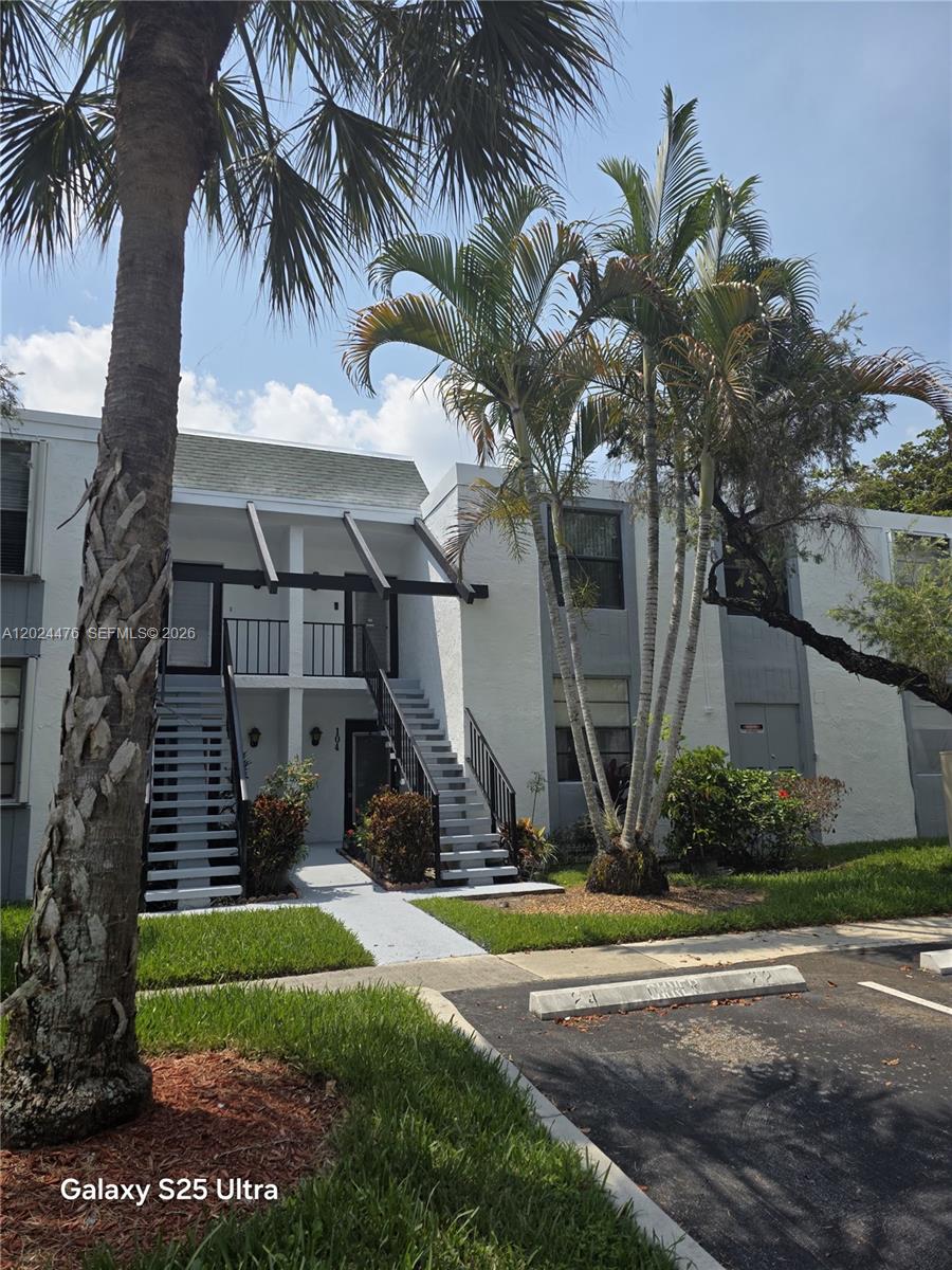 A two-story apartment building features exterior staircases leading to upper-level units — 7396 NW 18th St # 104, Margate FL 33063, MARGATE, FL