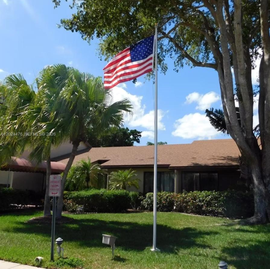 An American flag flies on a pole in front of a single-story house with landscaping — 7396 NW 18th St # 104, Margate FL 33063, MARGATE, FL