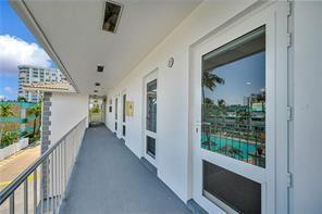 An exterior walkway with a metal railing overlooks a swimming pool and nearby buildings — 1461 S Ocean Boulevard # 328, Pompano Beach FL 33062, POMPANO BEACH, FL