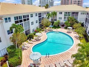 An aerial view of a kidney-shaped swimming pool surrounded by a patio and apartment buildings — 1461 S Ocean Boulevard # 328, Pompano Beach FL 33062, POMPANO BEACH, FL