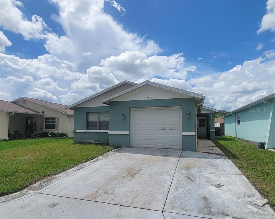 A single-story house with a teal exterior, a one-car garage, and a concrete driveway — 12639 SKIPPER LANE, HUDSON, FL