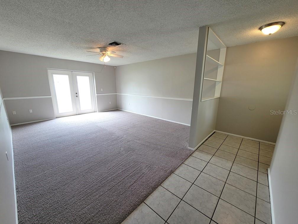 A living room features carpeted flooring, a ceiling fan, French doors, and a tiled entryway — 12639 SKIPPER LANE, HUDSON, FL