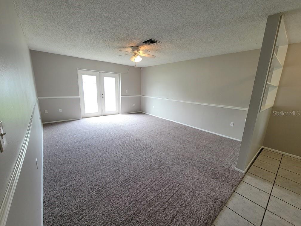 A carpeted living room features a ceiling fan, chair rail molding, and double glass doors — 12639 SKIPPER LANE, HUDSON, FL