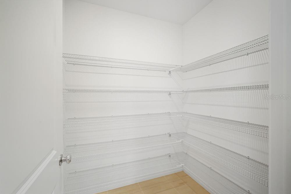 A walk-in pantry features white wire shelving installed on three walls above tiled flooring — 13520 TROPICAL BREEZE WAY, HUDSON, FL