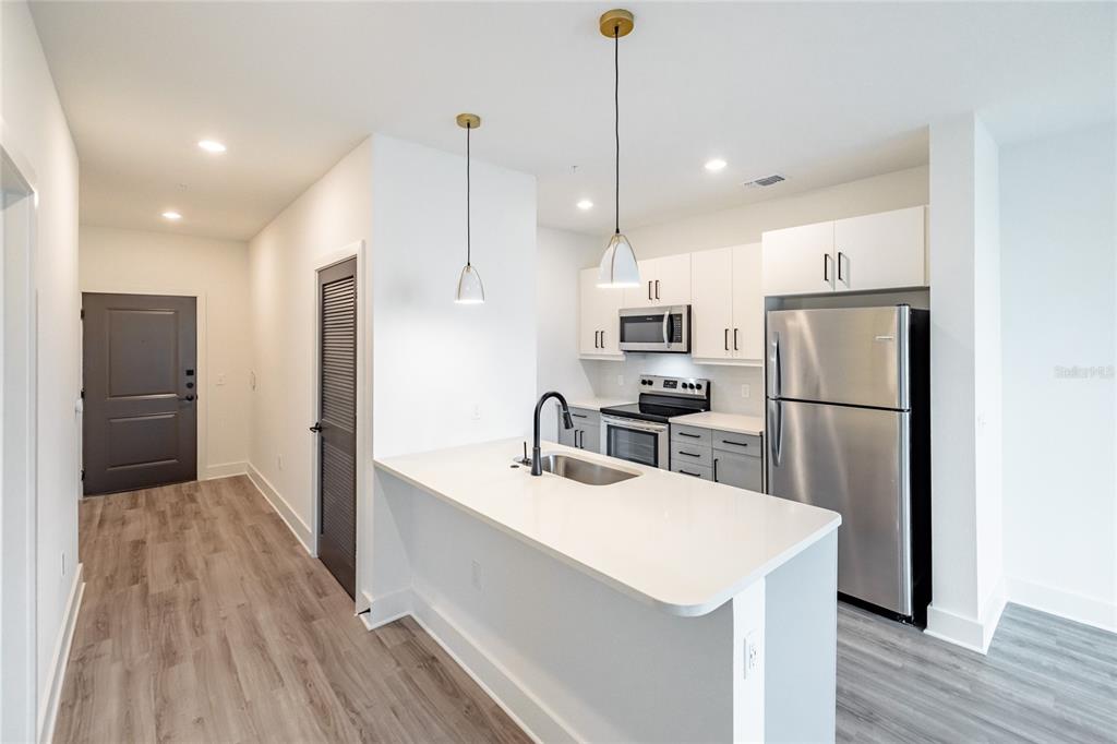 A modern kitchen features white cabinets, stainless steel appliances, and a white quartz island countertop — 1420 LAKEFRONT DRIVE UNIT ST-3303, SARASOTA, FL