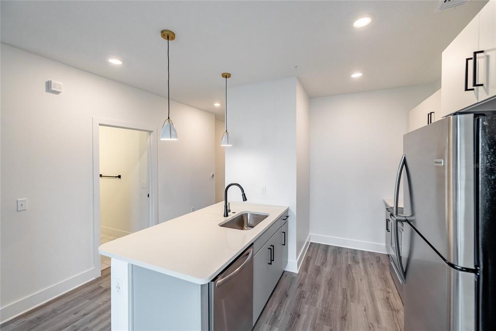 A modern kitchen features a white island with a sink, stainless appliances, and wood-look flooring — 1420 LAKEFRONT DRIVE UNIT ST-3303, SARASOTA, FL