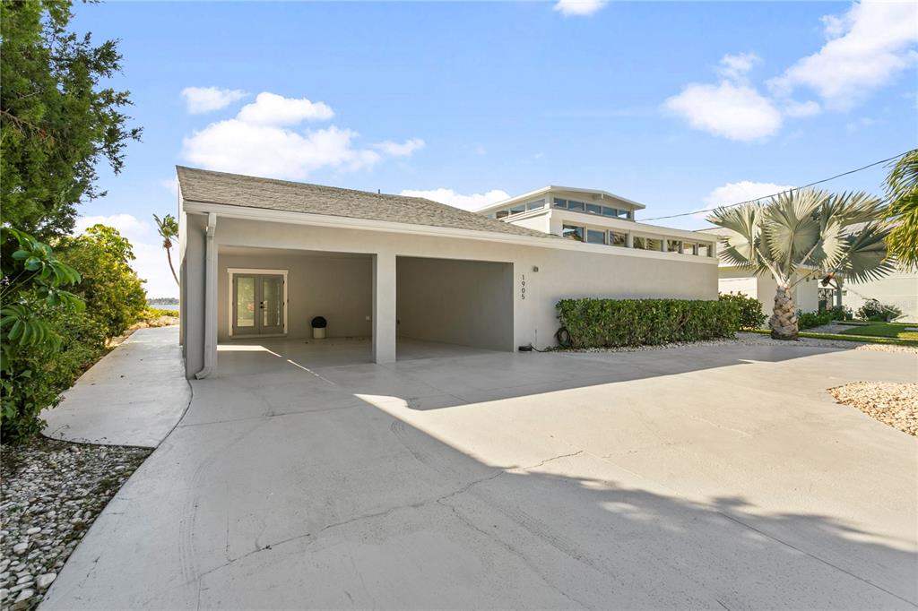 A two-car carport is attached to a light-colored house with a concrete driveway — 1905 4TH STREET W, PALMETTO, FL