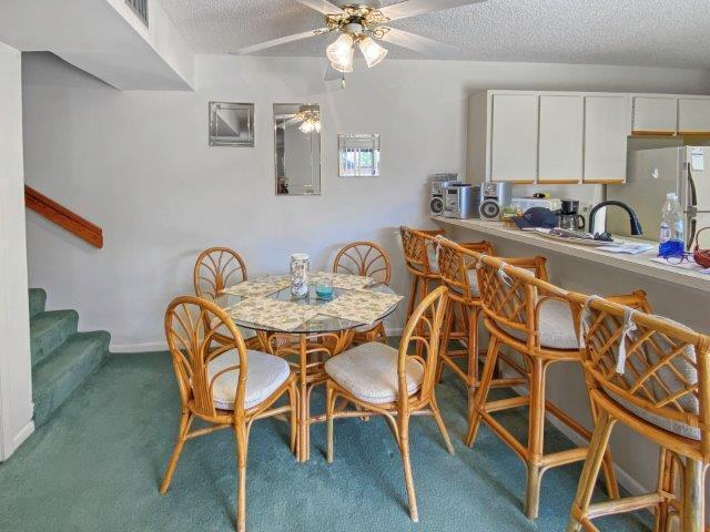 A dining area with a glass table and rattan chairs sits beside a kitchen counter — 62 Springdale Circle, Palm Springs FL 33461, PALM SPRINGS, FL