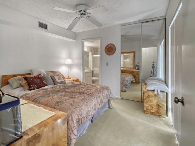 A bedroom features a bed with patterned bedding, a ceiling fan, and mirrored closet doors — 62 Springdale Circle, Palm Springs FL 33461, PALM SPRINGS, FL