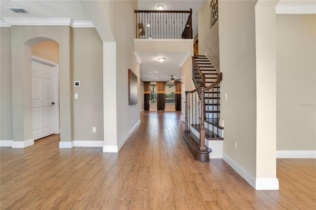 An entryway features wood-look tile flooring, a wooden staircase with iron railings, and high ceilings — 2356 KELBROOK COURT, OVIEDO, FL