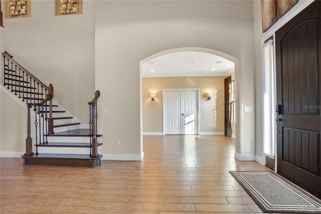 A foyer features wood-look tile flooring, a staircase with dark wood railings, and an arched entryway — 2356 KELBROOK COURT, OVIEDO, FL