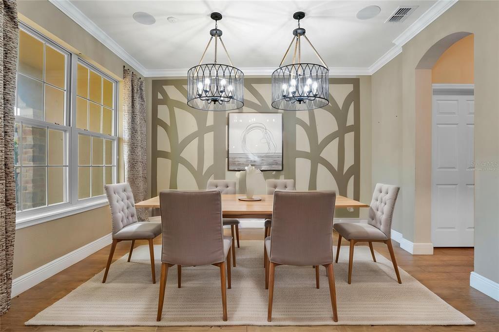 A dining room features a wooden table, six upholstered chairs, and two large metal chandeliers — 2356 KELBROOK COURT, OVIEDO, FL