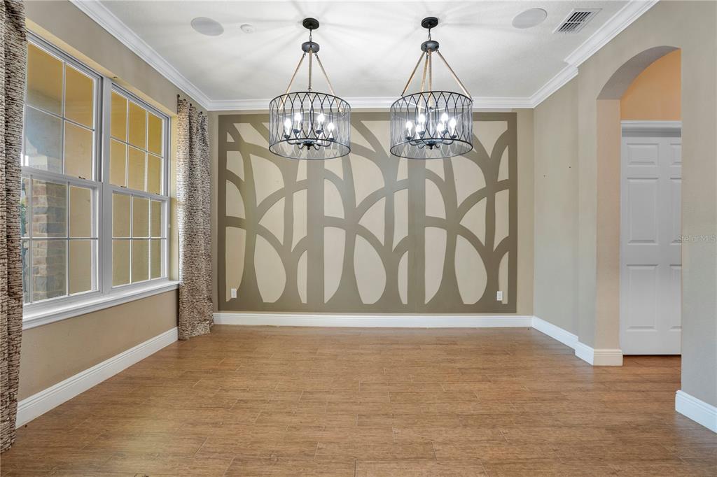 A dining room features wood-look tile floors, two drum chandeliers, and a decorative accent wall — 2356 KELBROOK COURT, OVIEDO, FL