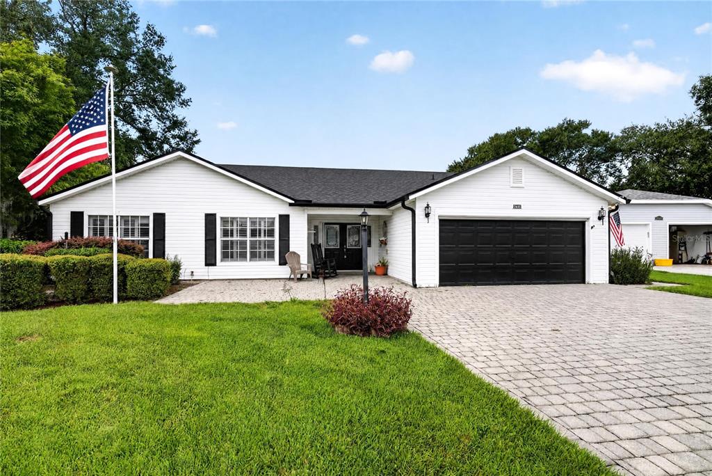 A white single-story house with a black garage door and a paved driveway — 25102 MERIWEATHER ROAD, LEESBURG, FL