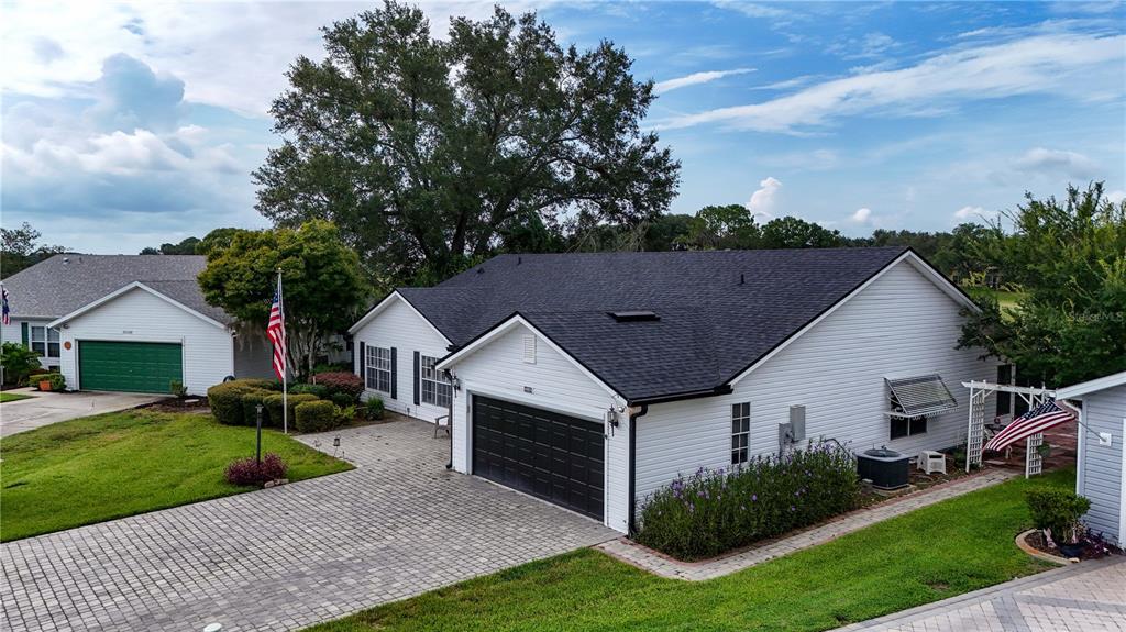 An exterior view of a white house with a black roof and a paved driveway — 25102 MERIWEATHER ROAD, LEESBURG, FL