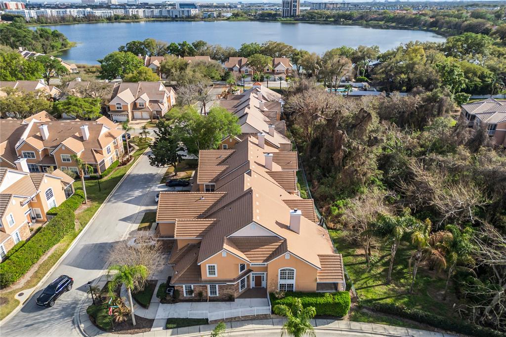 An aerial view shows a multi-unit townhouse complex with tan stucco walls and brown roofs — 7000 STONEHEDGE DRIVE UNIT 156, ORLANDO, FL