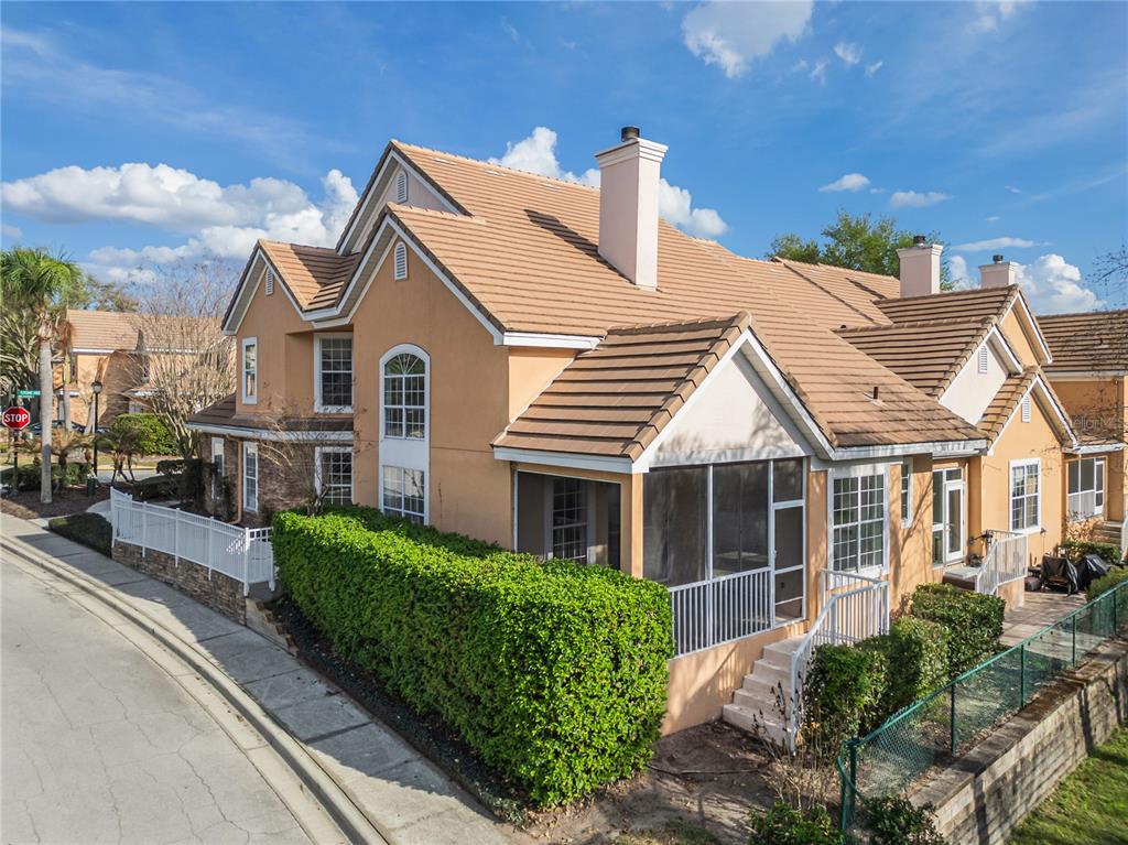 An exterior view of a two-story tan stucco townhouse with a tiled roof and patio — 7000 STONEHEDGE DRIVE UNIT 156, ORLANDO, FL