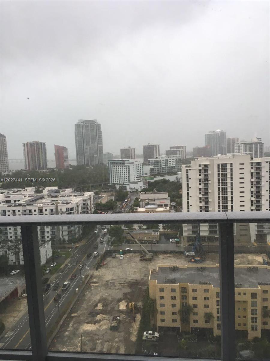 A high-angle view from a balcony overlooks a city street, construction site, and skyline — MIAMI, FL