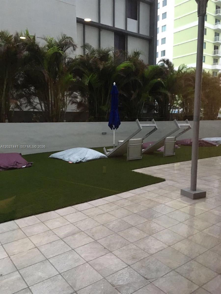 An outdoor patio features artificial turf, lounge chairs, beanbag cushions, and a blue umbrella — MIAMI, FL