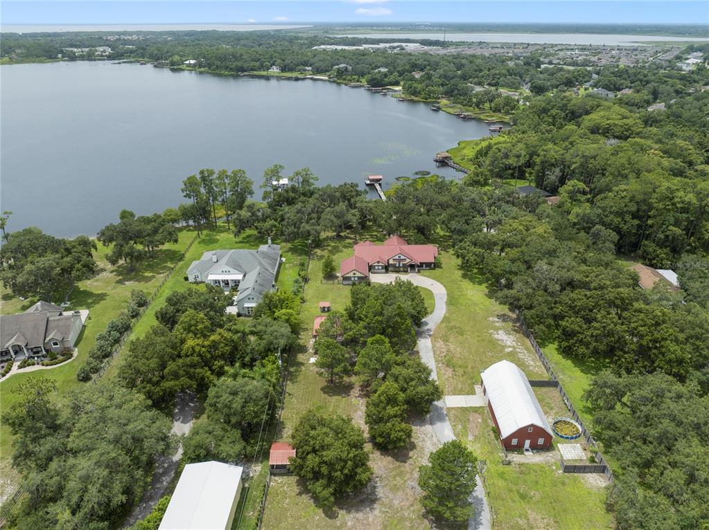 An aerial view shows a large waterfront property with multiple buildings, a driveway, and trees — 2700 ZUNI ROAD, ST CLOUD, FL