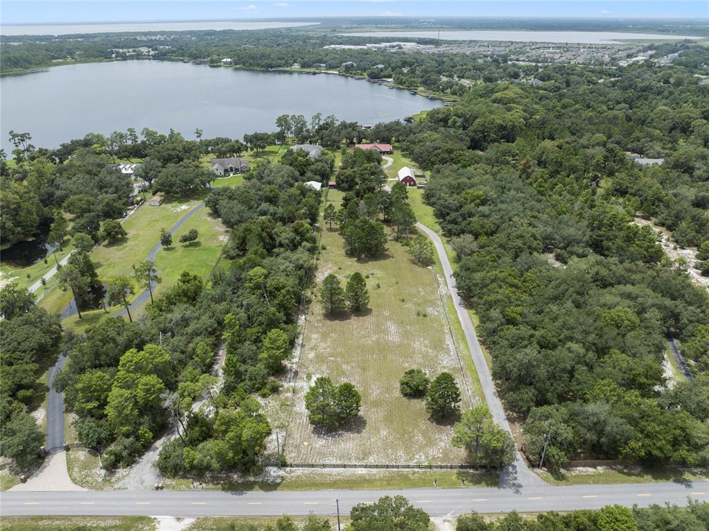 An aerial view shows a rectangular, grassy lot bordered by trees and a paved road — 2700 ZUNI ROAD, ST CLOUD, FL
