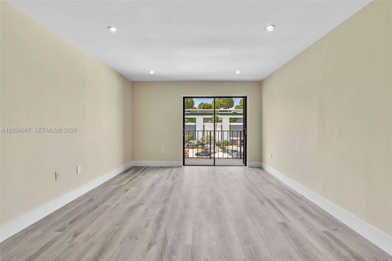 An empty room features light-colored wood-look flooring, beige walls, recessed lighting, and a sliding door — 9124 Collins Ave # 304, Surfside FL 33154, SURFSIDE, FL