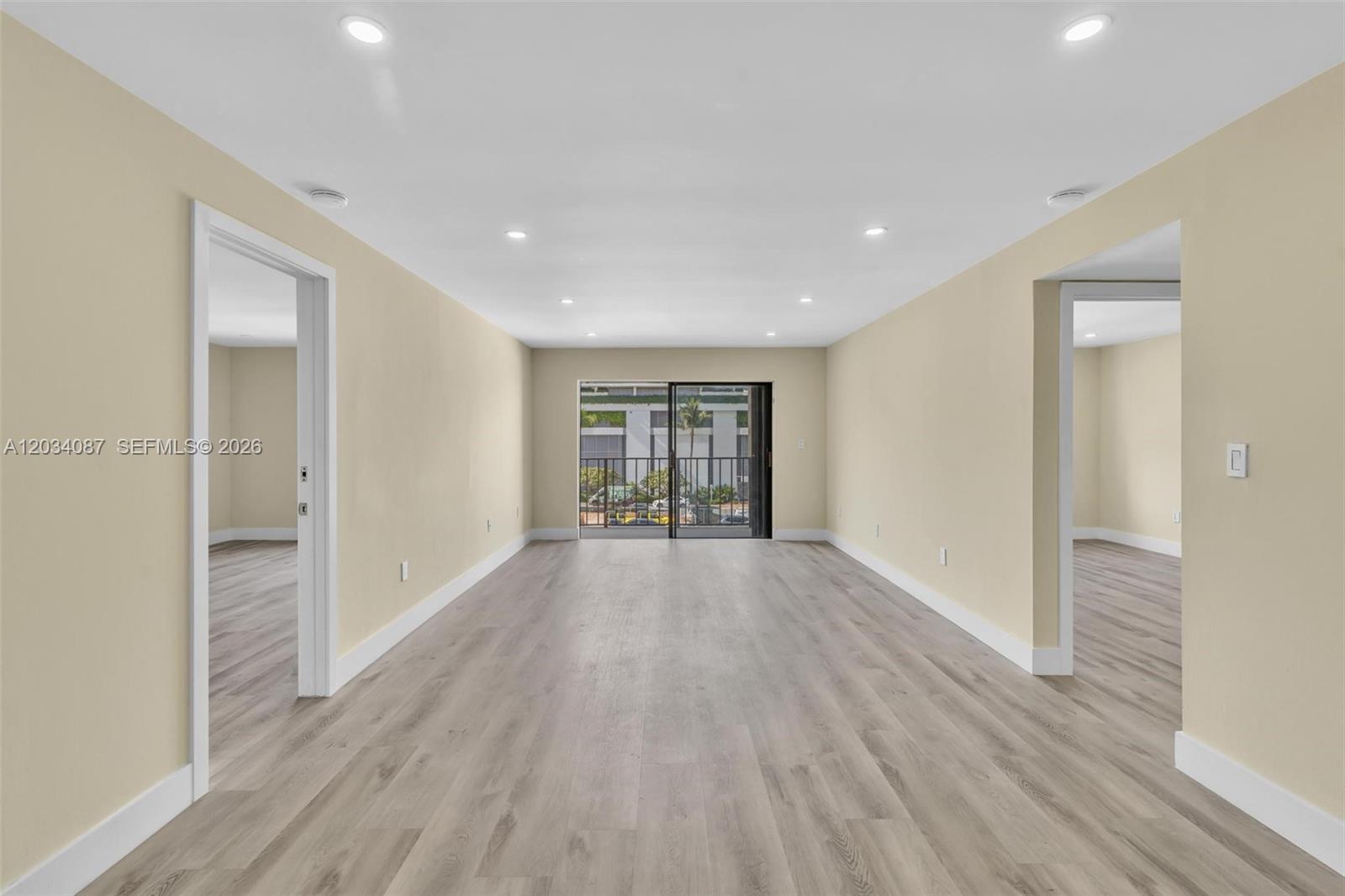 An empty room with light-colored walls, wood-look flooring, recessed lighting, and a sliding glass door — 9124 Collins Ave # 304, Surfside FL 33154, SURFSIDE, FL
