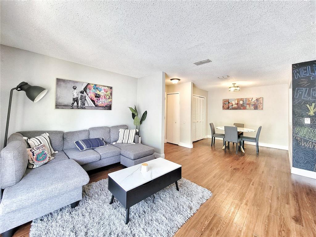 A living room with a gray sectional sofa, coffee table, and adjacent dining area — 3705 SW 27TH STREET UNIT 527, GAINESVILLE, FL
