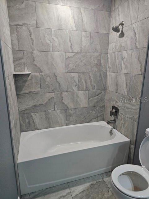 A bathroom features a white bathtub with a gray tiled surround and a shower head — 650 NW 5TH STREET, OCALA, FL