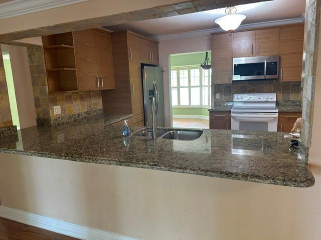 A kitchen features granite countertops, wood cabinets, a stainless steel refrigerator, and a tile backsplash — 732 SE 11th Avenue, Deerfield Beach FL 33441, DEERFIELD BEACH, FL