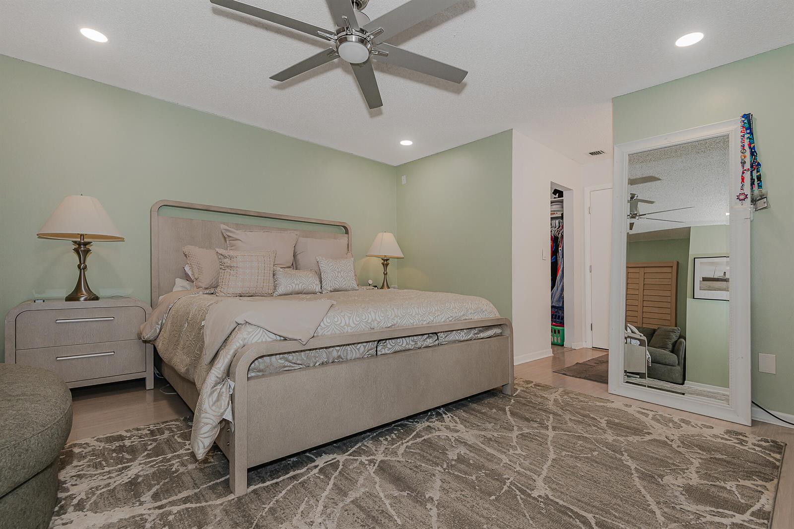 A bedroom with sage green walls, a light wood bed frame, and a large floor mirror — 4 Verwood Way, Boynton Beach FL 33426, BOYNTON BEACH, FL