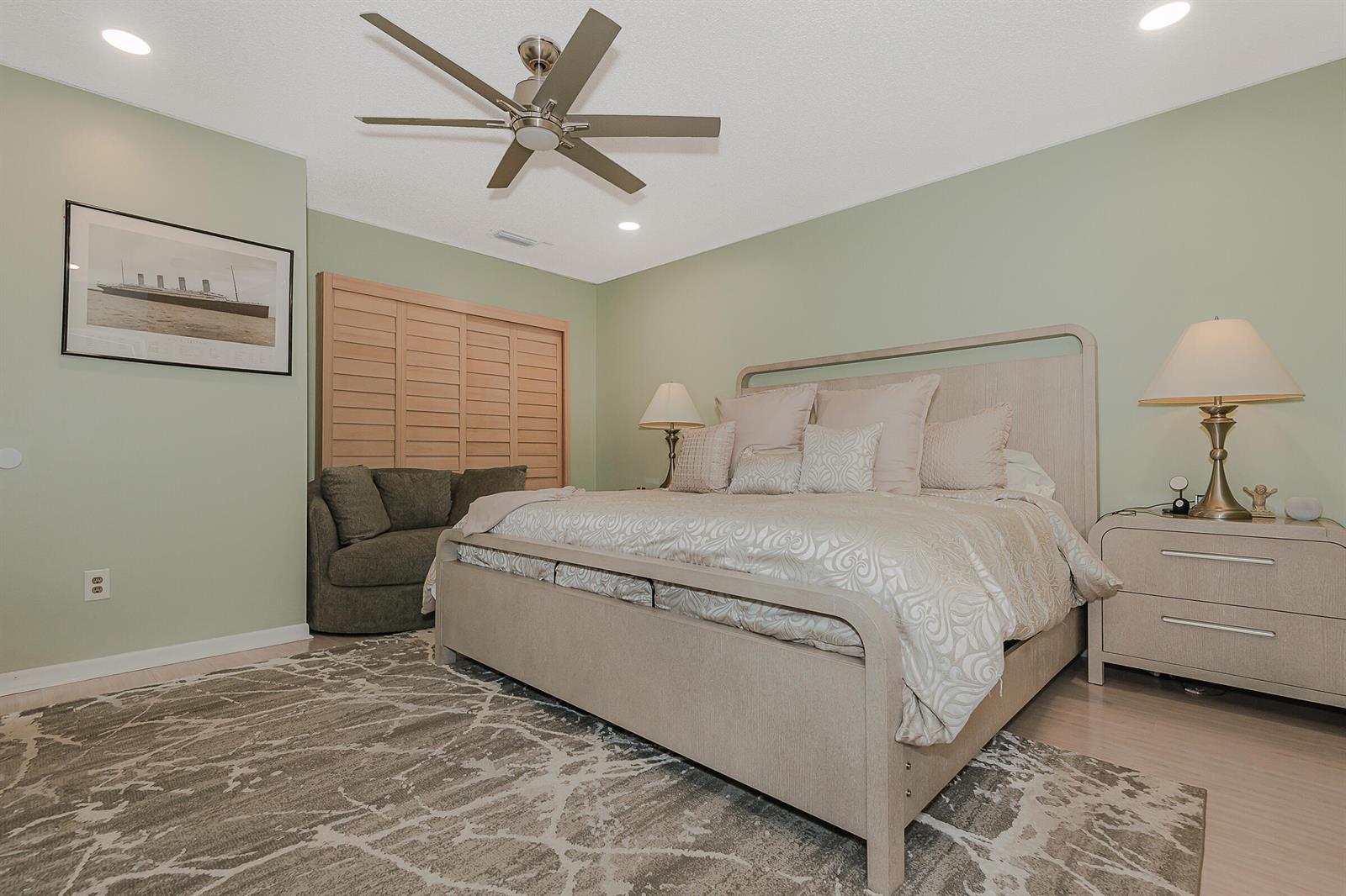 A bedroom features a light-colored bed, a patterned area rug, and sage green walls — 4 Verwood Way, Boynton Beach FL 33426, BOYNTON BEACH, FL