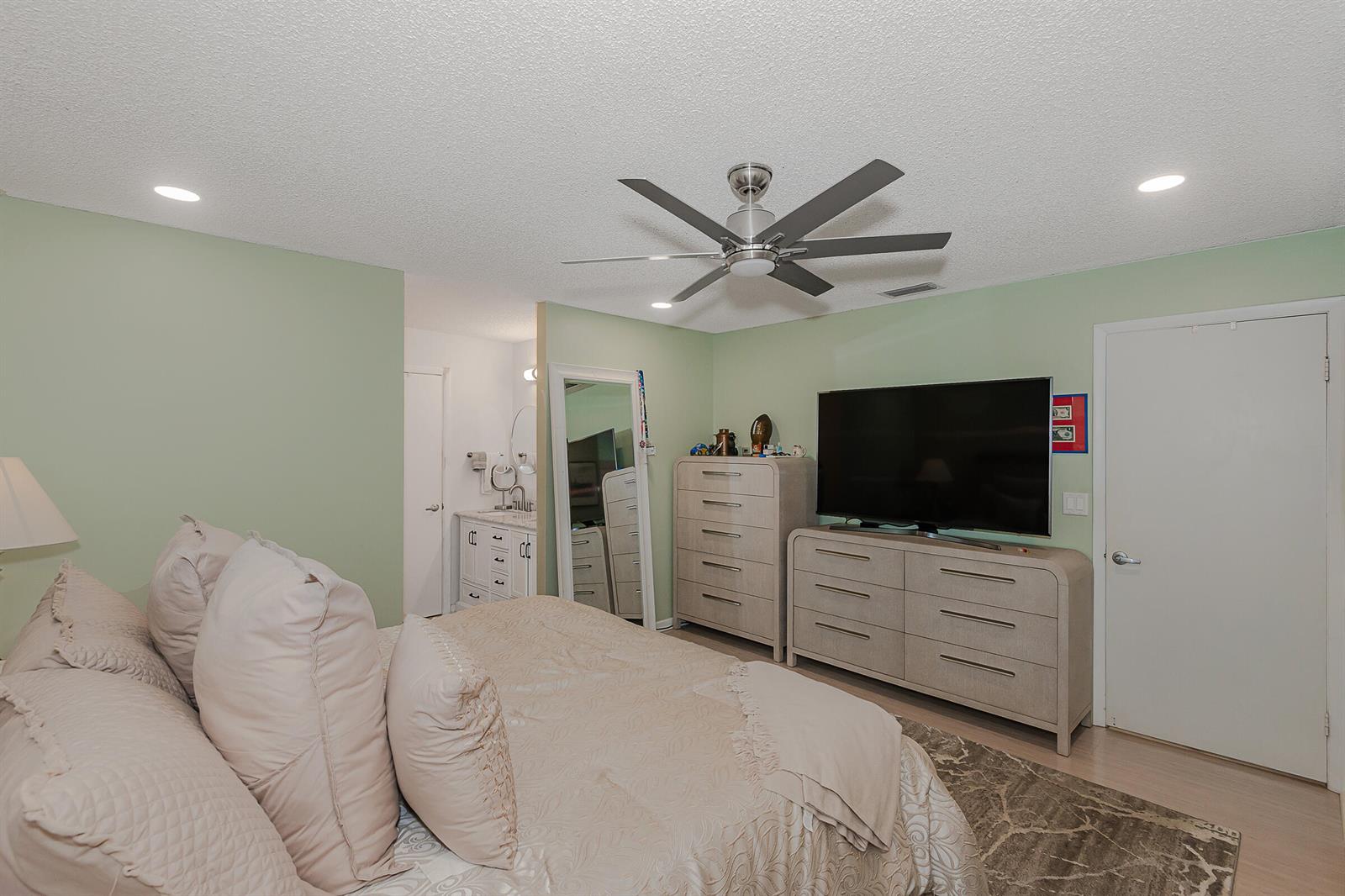 A bedroom features light green walls, a ceiling fan, a television, and light-colored furniture — 4 Verwood Way, Boynton Beach FL 33426, BOYNTON BEACH, FL