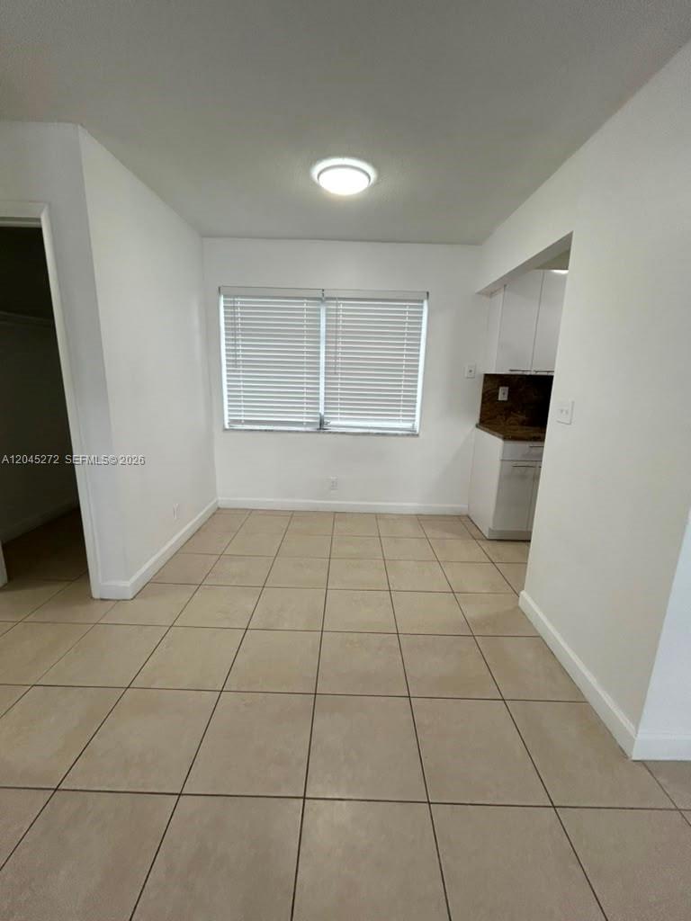 A dining area features white walls, a single window with blinds, and light-colored tile flooring — 2435 Van Buren St APT 1B, Hollywood FL 33020, HOLLYWOOD, FL