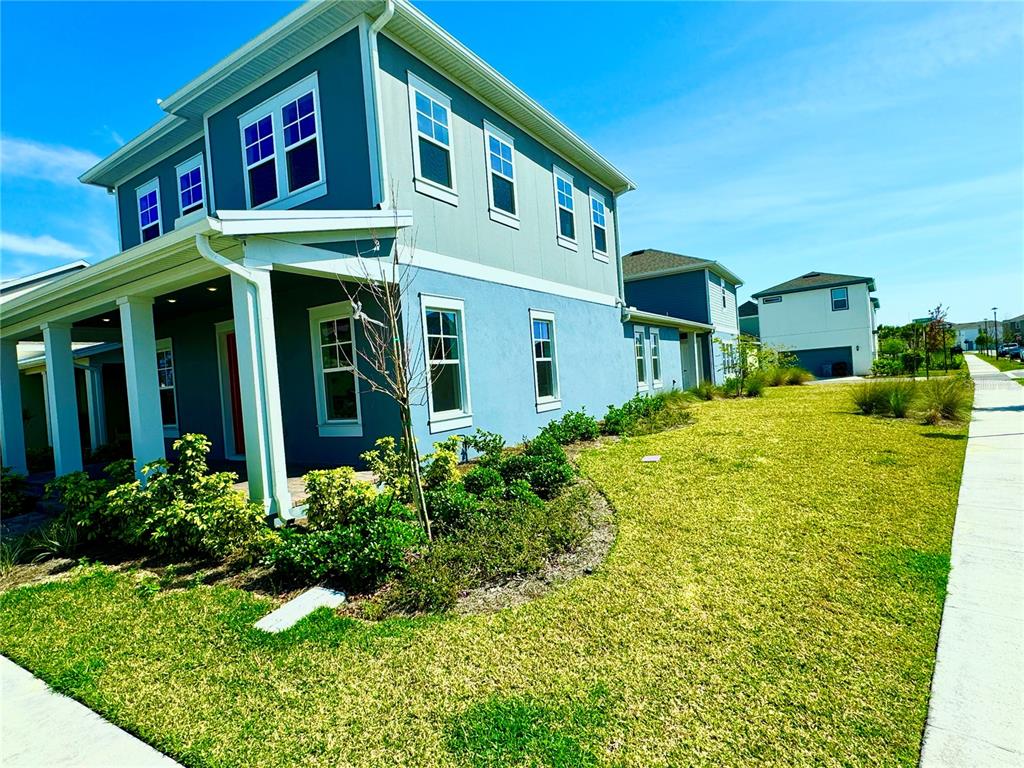 A two-story blue house with a covered porch and a grassy side yard — 9726 NERUDA STREET, ORLANDO, FL
