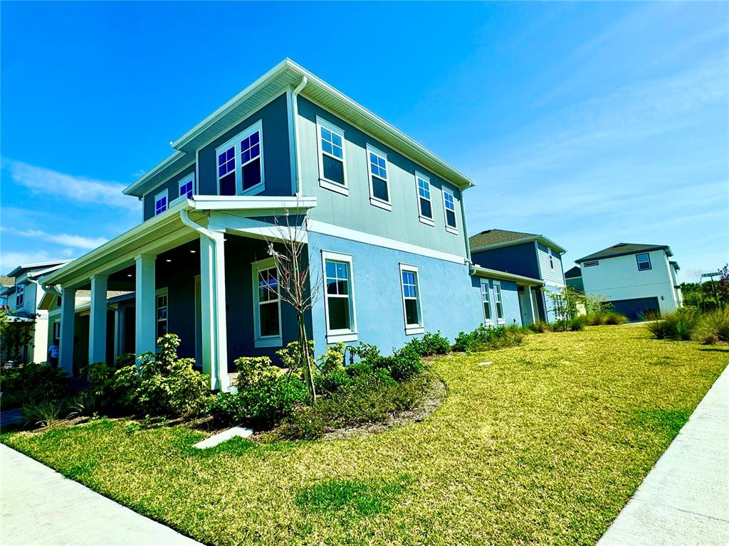 A two-story blue house with a front porch and a grassy yard under a blue sky — 9726 NERUDA STREET, ORLANDO, FL