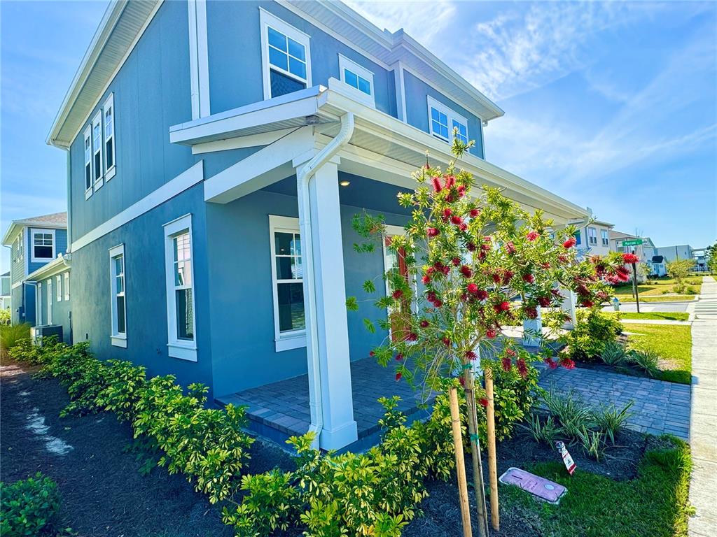 A blue two-story house with a front porch, white trim, and a flowering tree — 9726 NERUDA STREET, ORLANDO, FL
