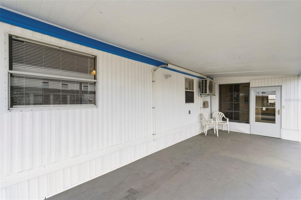 A covered patio with white vertical siding, a window, and a door to the home — 10826 TIOGA DRIVE, PORT RICHEY, FL