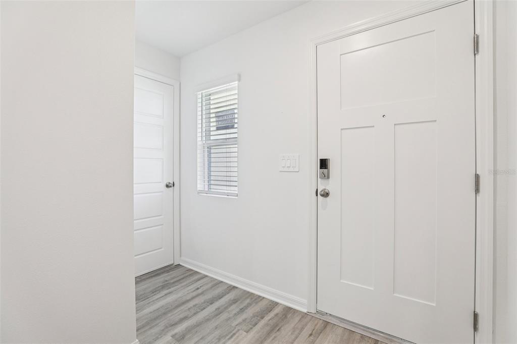 An entryway features white walls, light wood-look flooring, a front door, and a side door — 1227 CUMBERLAND TRAIL DRIVE, LAKE HAMILTON, FL