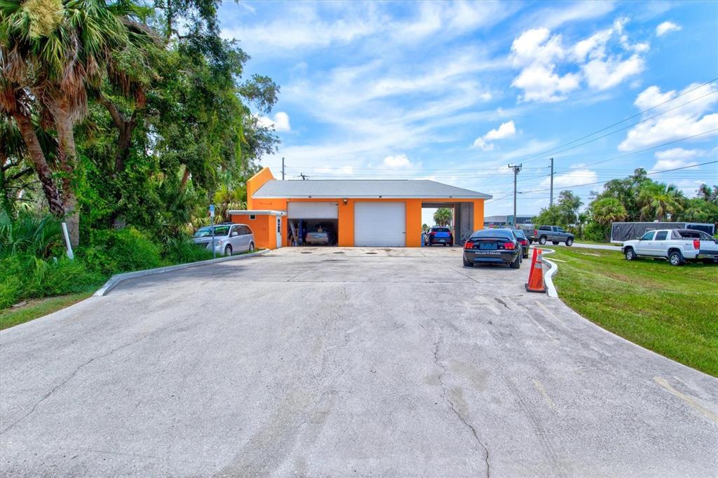 An orange commercial garage building with two bay doors sits on a paved lot — 15182 DAHLGREN AVENUE, PORT CHARLOTTE, FL