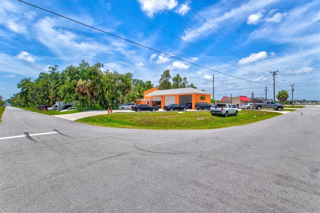 An orange commercial building with multiple garage bays sits on a corner lot — 15182 DAHLGREN AVENUE, PORT CHARLOTTE, FL