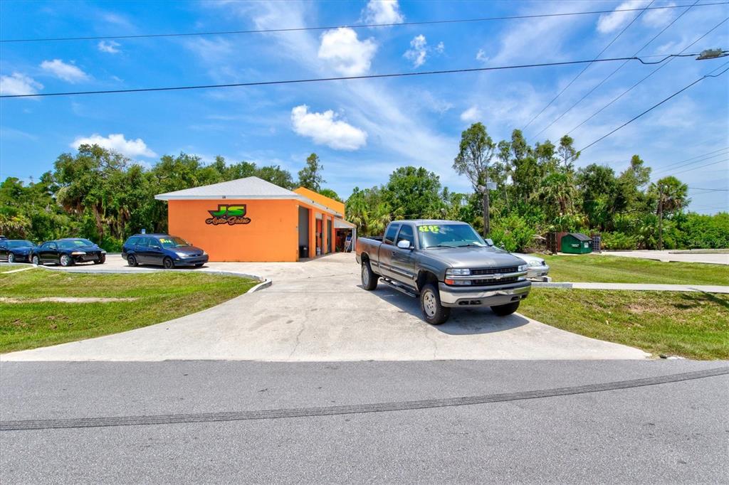 An orange commercial building with a concrete driveway and several parked vehicles — 15182 DAHLGREN AVENUE, PORT CHARLOTTE, FL
