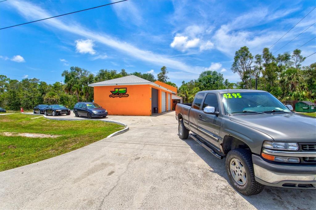 An orange commercial building with a gray pickup truck parked in the foreground — 15182 DAHLGREN AVENUE, PORT CHARLOTTE, FL